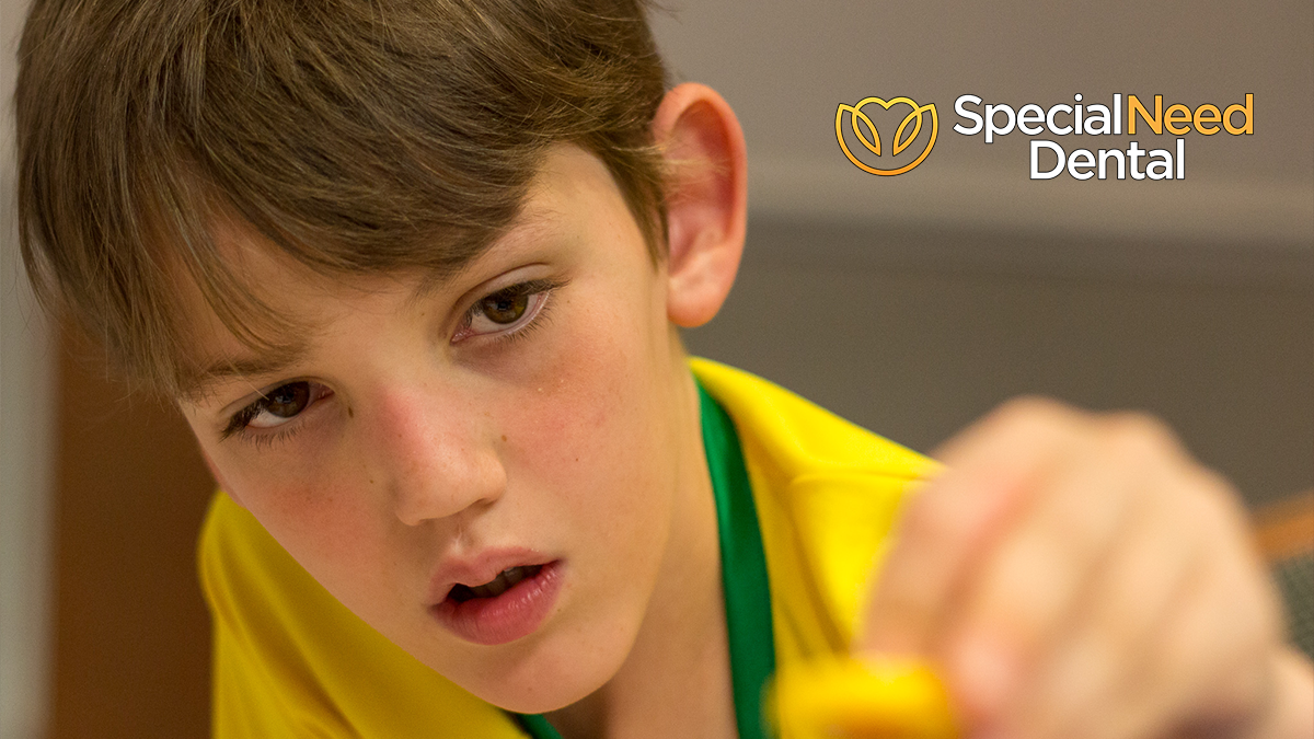 a boy in a yellow shirt with fragile x syndrome and the logo for special need dental